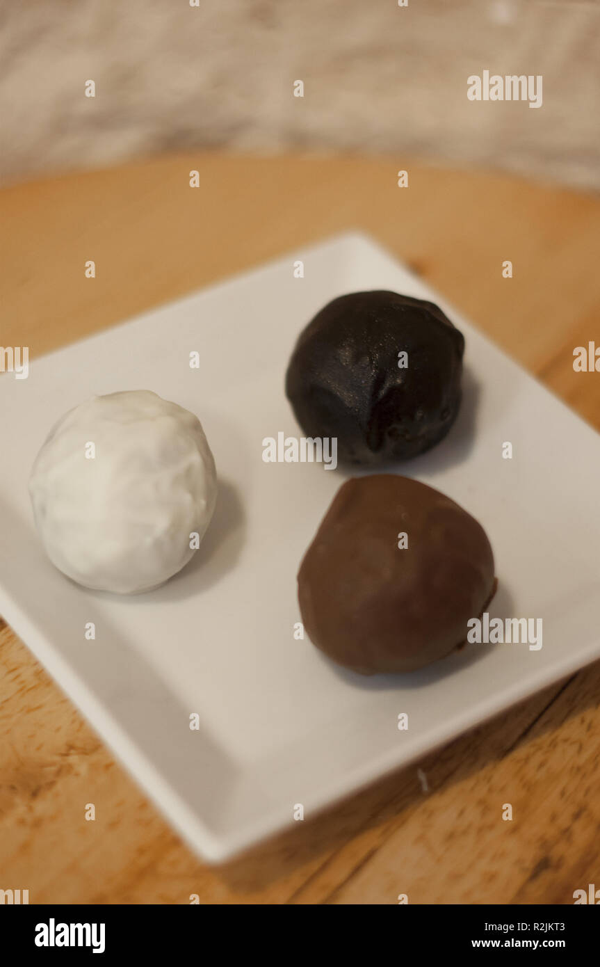 Köstliche weiße, Milch und dunkle Schokolade Kugeln auf hölzernen Tisch Stockfoto