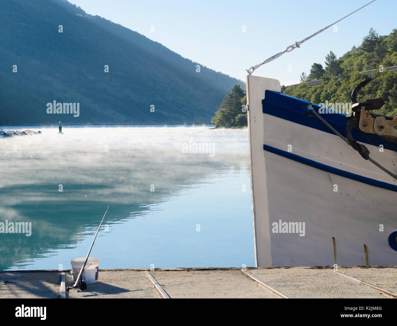 Kleines Fischerboot Bogen mit Morgennebel auf dem Meer in einem Abstand angedockt Stockfoto