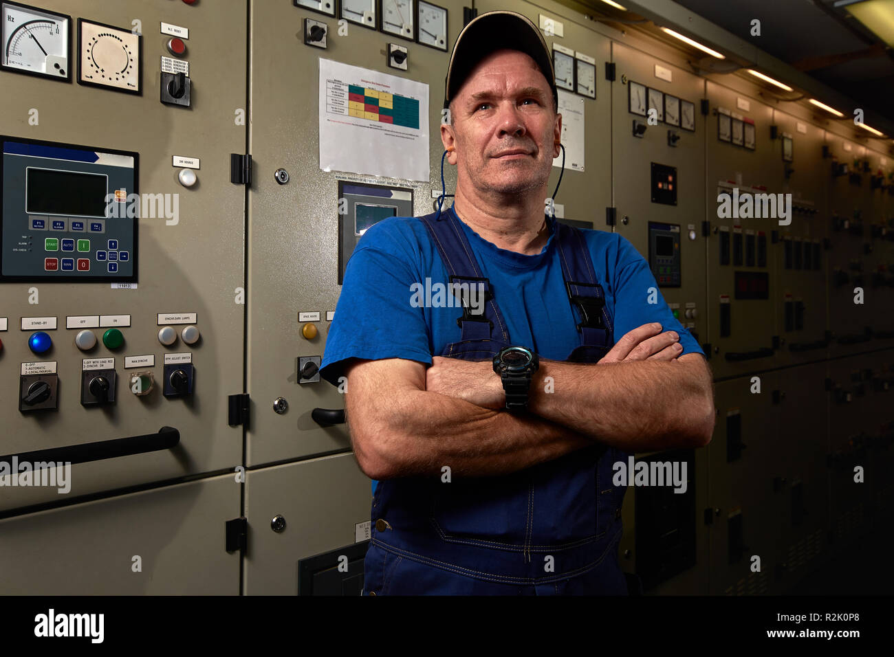 Stolz und glücklich Mechaniker/Chief Engineer, mit seinen Armen posing gekreuzt, lächelnd, zog in Uniform im Maschinenraum eines industriellen Frachtschiff. Stockfoto