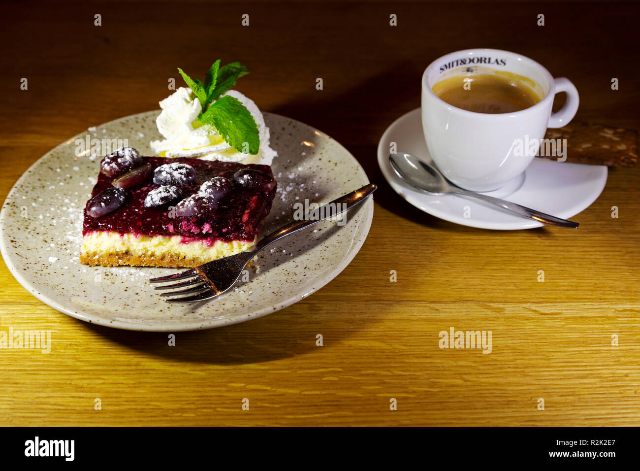 Käsekuchen mit Kaffee serviert. Der Käsekuchen wird mit Obst gekrönt und mit Minzcreme serviert. Stockfoto