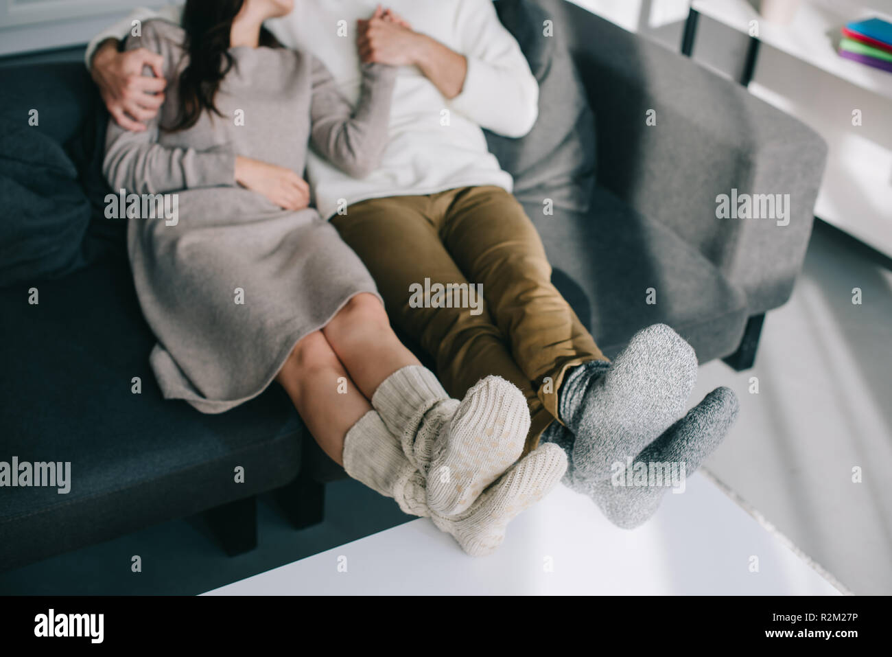 7/8 Schuß von Paar in warme Wollsocken entspannen auf der Couch zu Hause Stockfoto