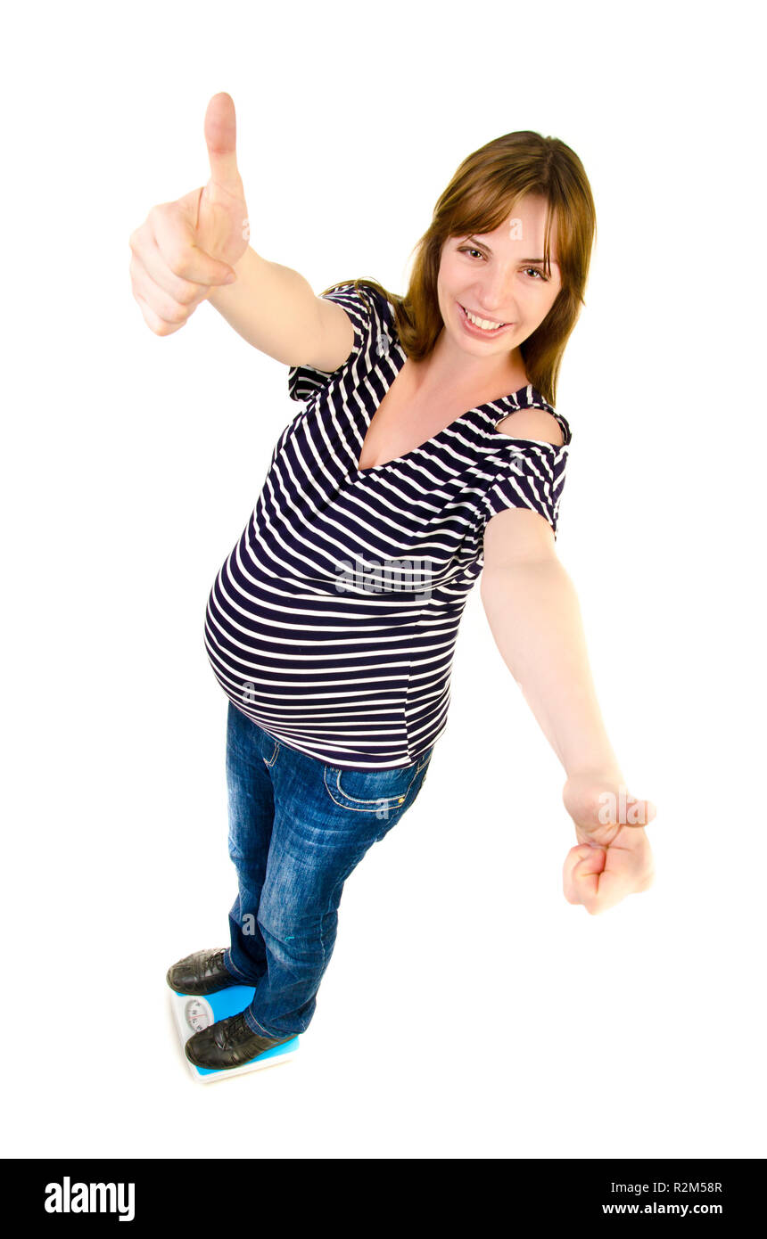 Schwangere Frau auf einer Waage mit einem Daumen hoch Stockfoto