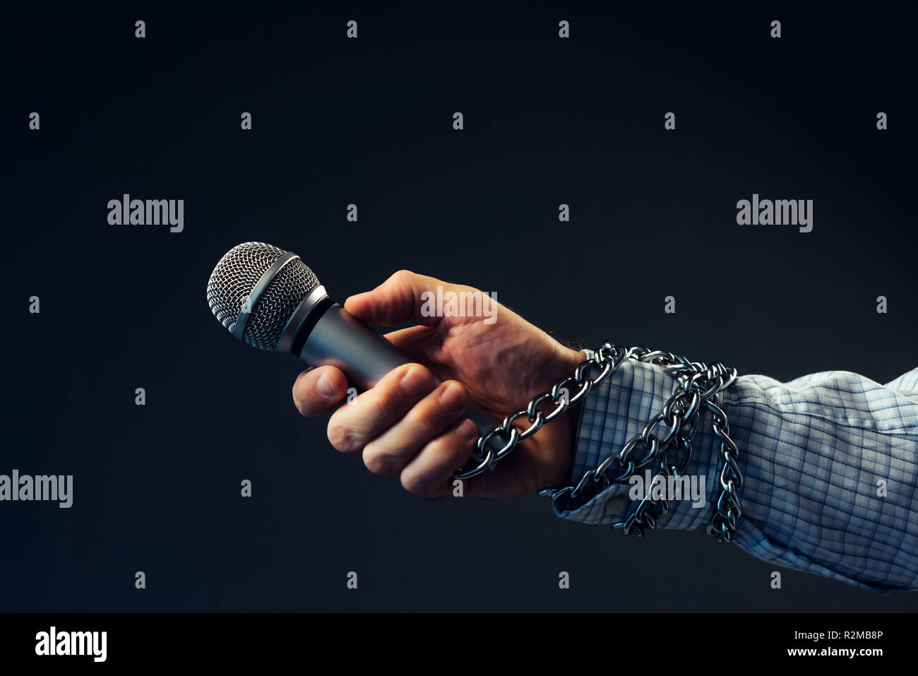 Die Freiheit der Presse und Journalismus, konzeptionelle Bild mit Mikrofon in männlicher Hand mit Ketten, Low Key Image gebunden Stockfoto