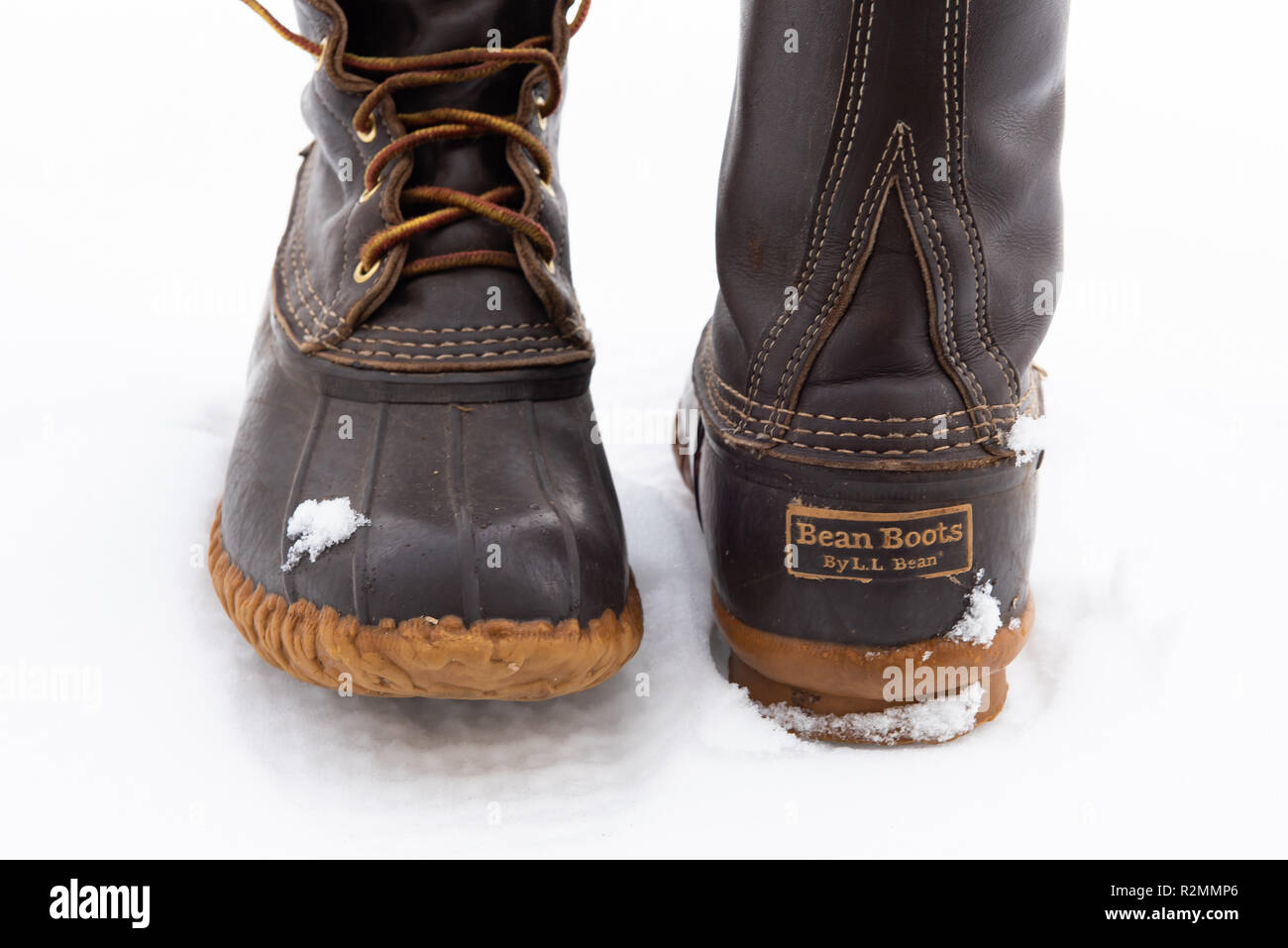 Ein paar abgenutzte LL Bean Stiefel im Schnee, mit dem Leder und Gummi Bau und die markanten Kettenglied Profil und wasserdichte Sohle. Stockfoto