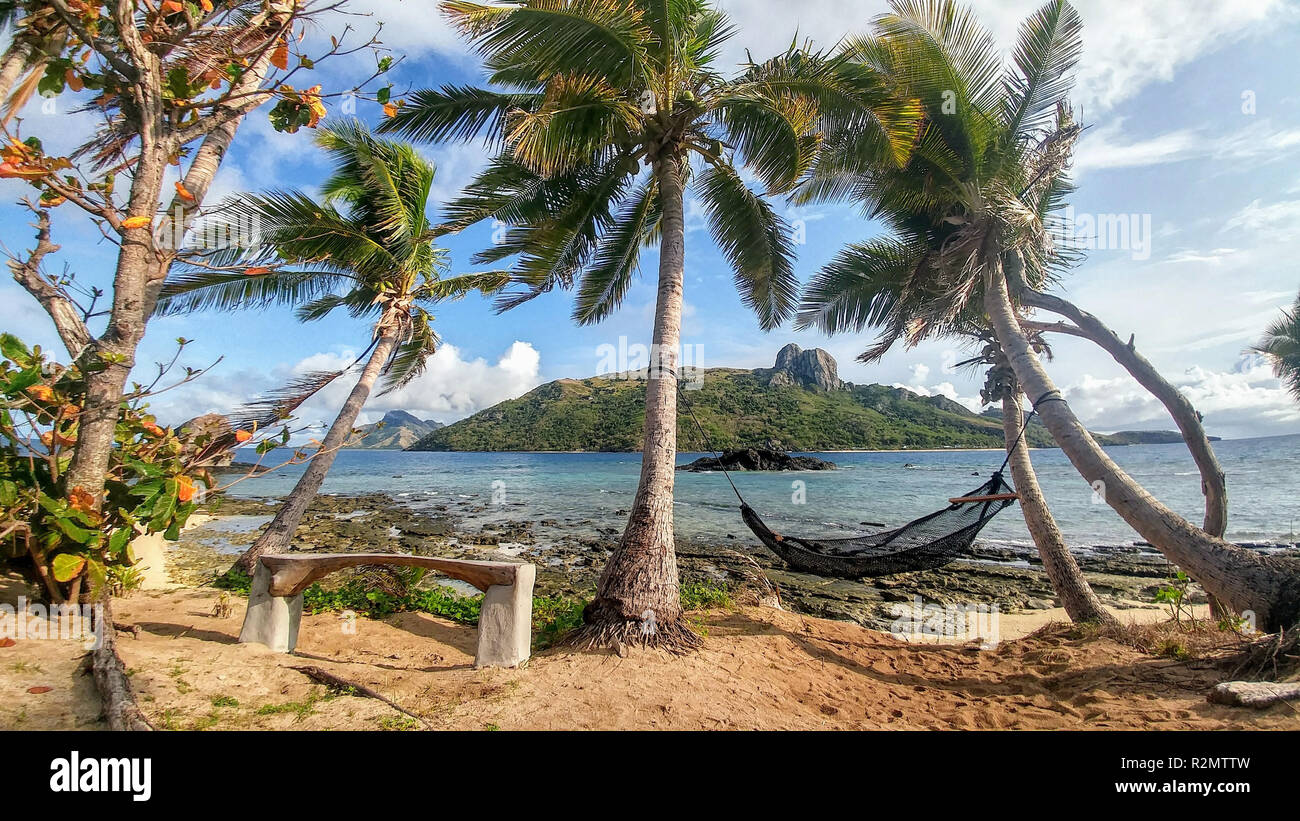 Hängematte zwischen zwei Palmen am Meer und Blick auf Waya Island, Fidschi Stockfoto