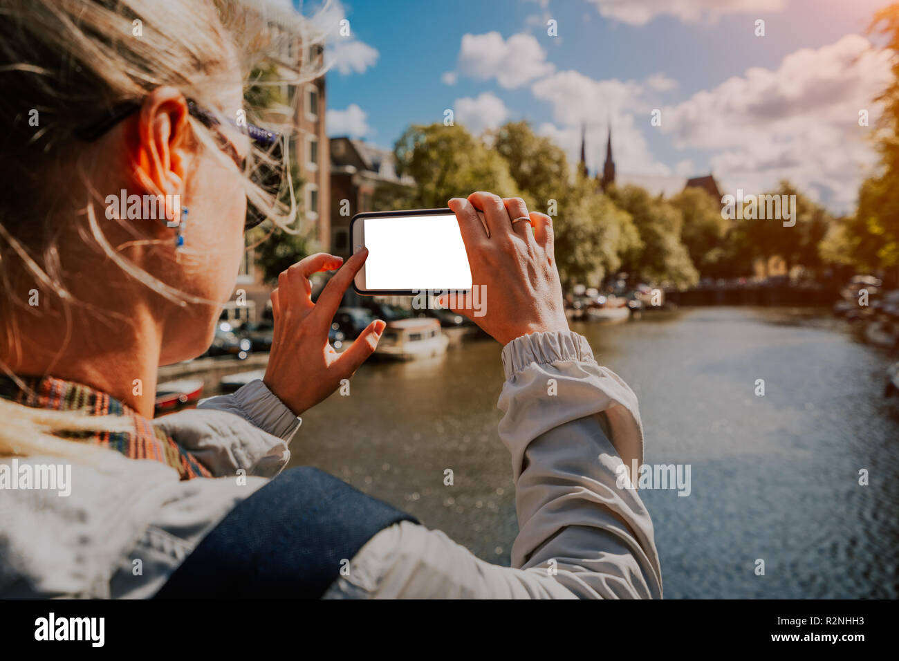 Frau Tourist, der ein Bild von Canal in Amsterdam auf dem Mobiltelefon. Warme gold Nachmittag Sonne. Reisen in Europa Stockfoto