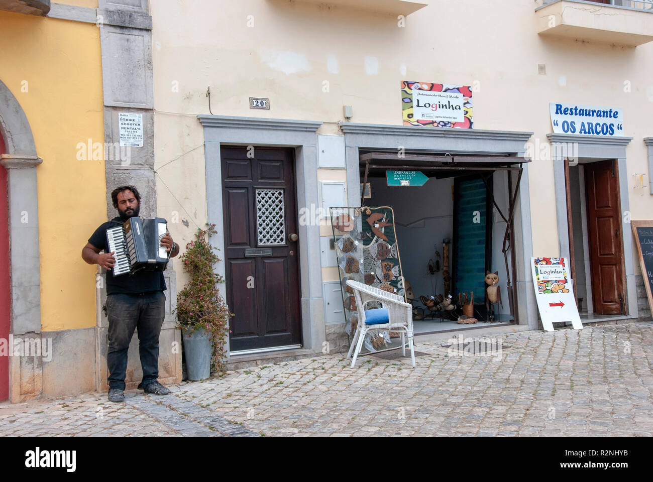 Poruguese Gaukler spielen Akkordeon im gepflasterten Straße Tavira Portugal dunkelhäutige portugiesischen Mann mit schwarzem Haar Bart Musiker Gaukler straßenmusik Bettler Stockfoto