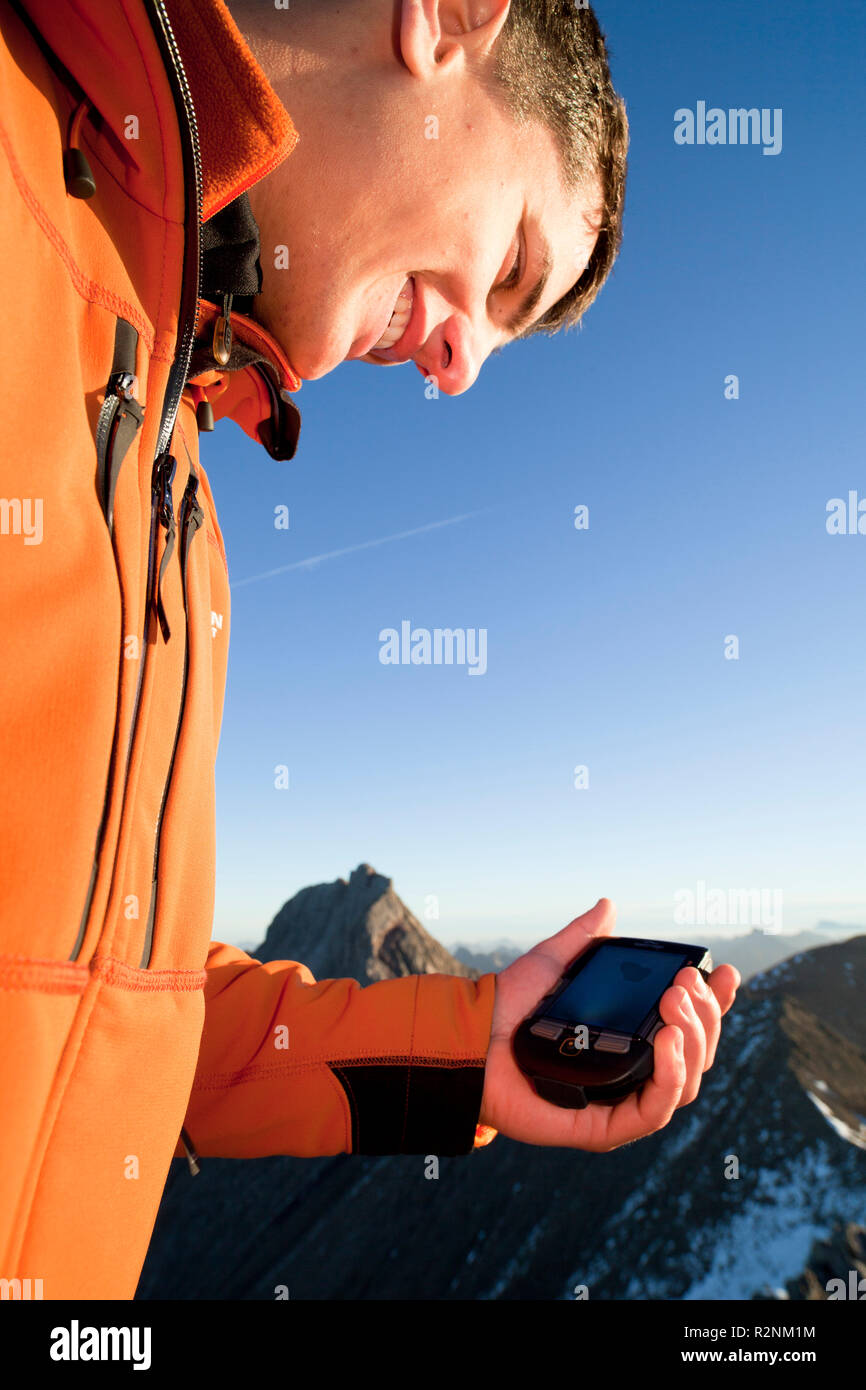 Kletterer mit GPS-Gerät am Gipfelgrat Dawinkopf, Lechtaler Alpen, Tirol, Österreich. Stockfoto