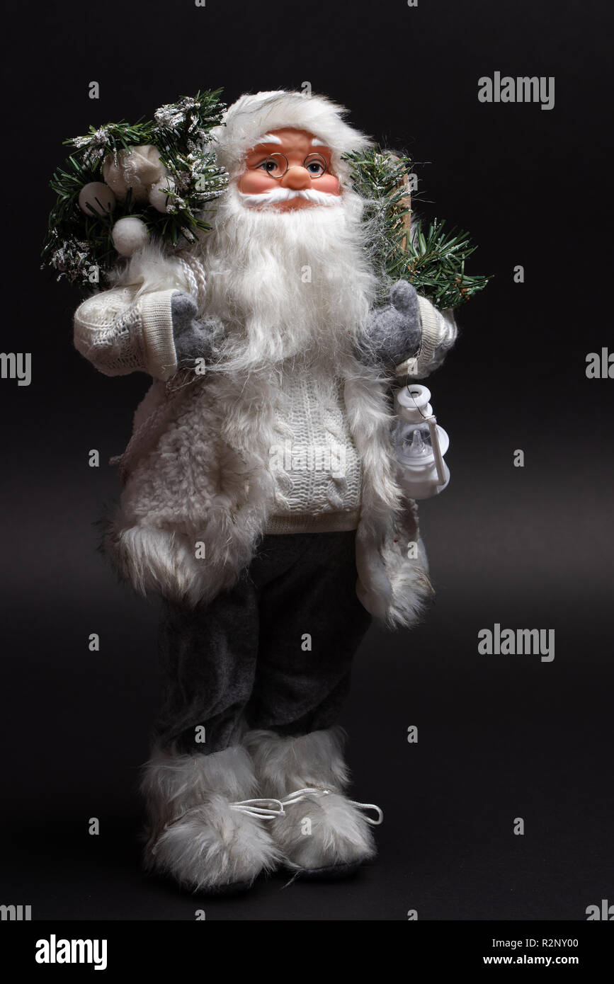 Close up Portrait von Santa Claus Spielzeug tragen graue Hosen und weiße Jacke. Schuss Einzel gegen dunklen Hintergrund Stockfoto