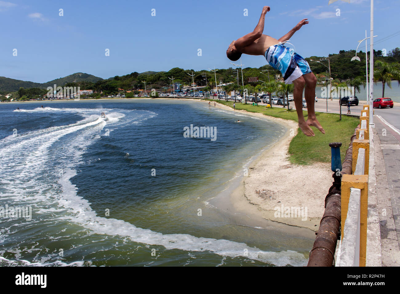 Mann springt zurück Salto von einer Brücke bei Lagoa da Conceição, Florianopolis, Brasilien Stockfoto