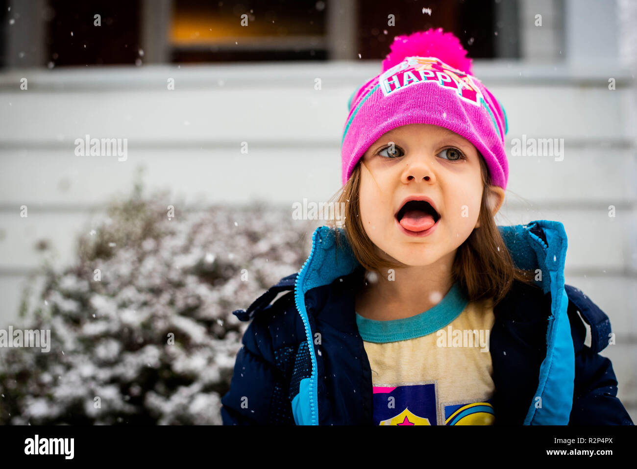 Ein kleines Mädchen Fänge Schneeflocken auf ihrer Zunge im kalten Winter Schnee. Stockfoto
