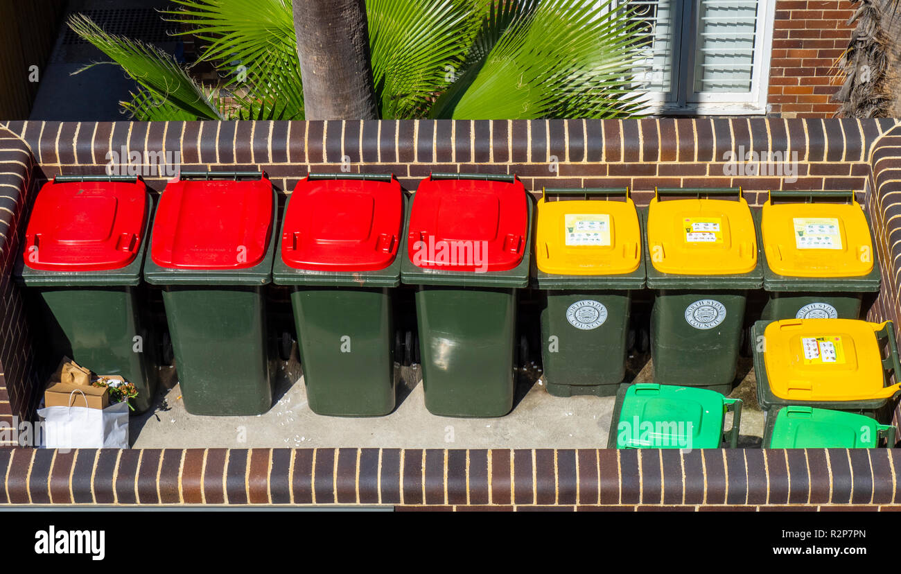 Farbcodierte Mülleimer, roter Deckel für den Allgemeinen Papierkorb, gelber Deckel für wiederverwertbaren Abfall, grün Deckel für Gartenabfälle. Stockfoto