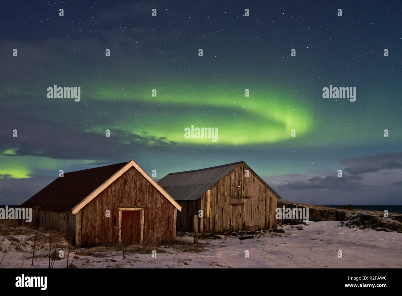 Zwei hölzernen Schuppen unter einer elliptischen Aurora Borealis Stockfoto