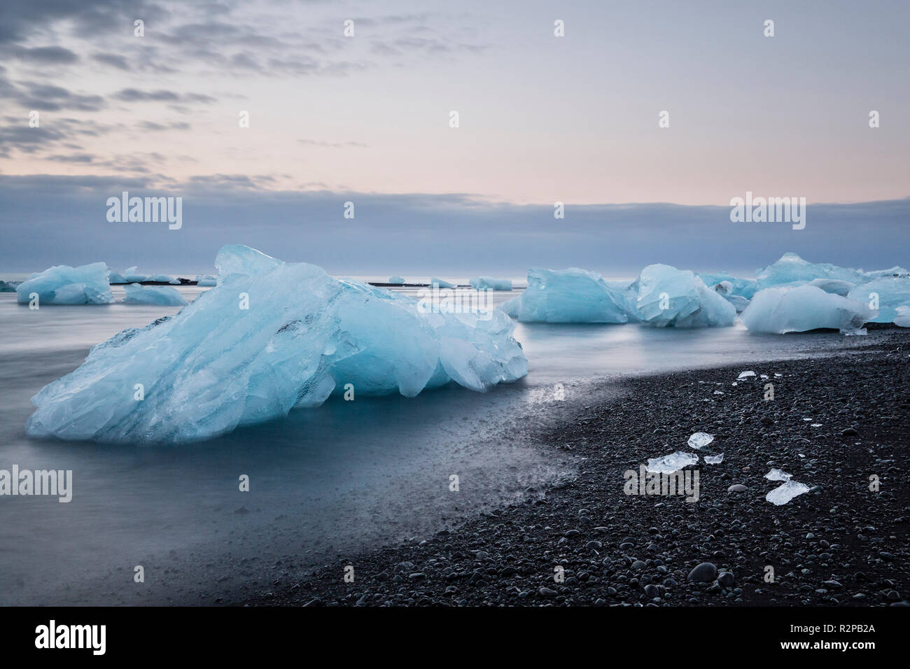 Blau schimmernden Eisblöcken in fliessend Wasser auf den schwarzen Strand von Jökulsárlón (Diamond Beach), Island, morgen stimmung Stockfoto
