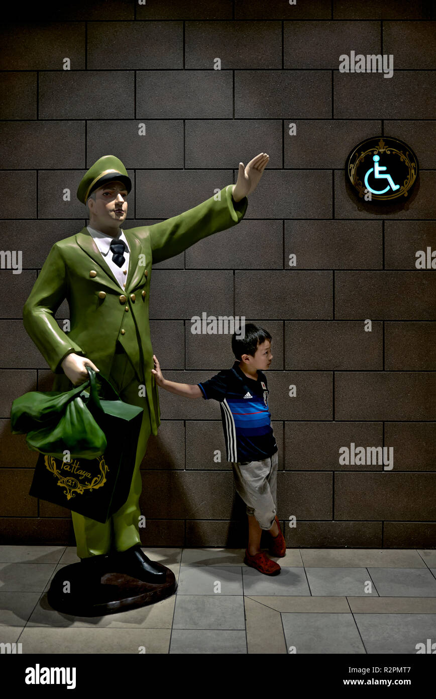 Lustig Kind. Amüsante ehrliches Bild von einer entspannten Kind gegen eine Statue in Erwartung der Rückkehr seiner Eltern aus der Toilette schiefen Stockfoto