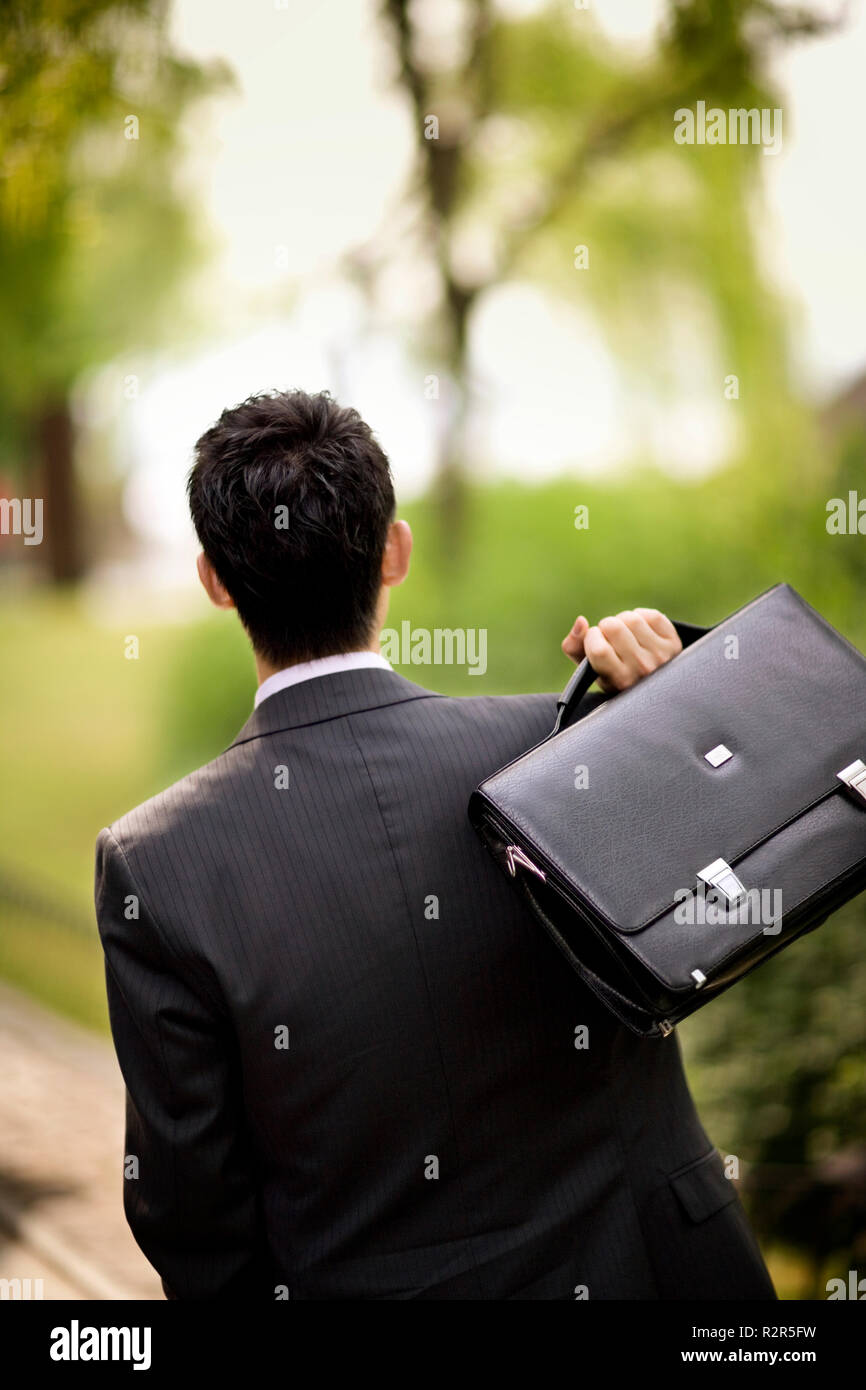 Ansicht der Rückseite des Geschäftsmann mit seiner Aktentasche schleuderte über die Schulter. Stockfoto