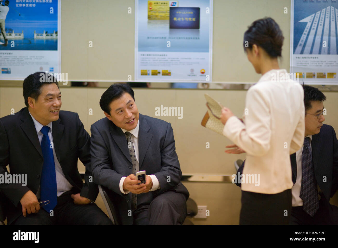 Zwei sitzende Unternehmer im Gespräch mit einer Kollegin. Stockfoto