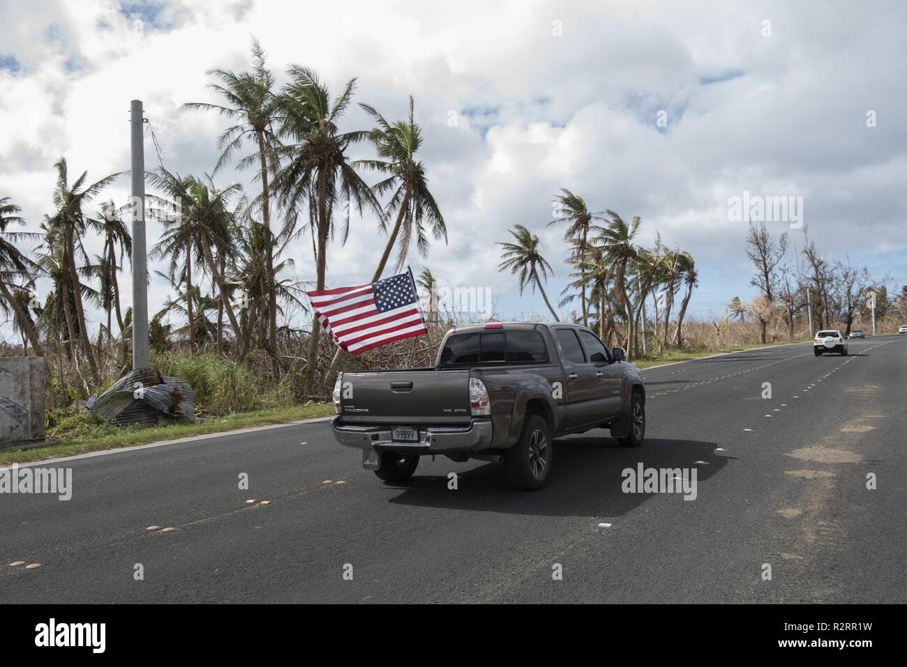 Ein Fahrzeug fährt mit einer amerikanischen Flagge schwenkten in der Luft in Saipan, Commonwealth der Nördlichen Marianen Nov. 2, 2018. Alle überall auf der Insel sichtbar sind Erinnerungen der Bürger lösen haben gezeigt nach Super Typhoon Yutu. Stockfoto