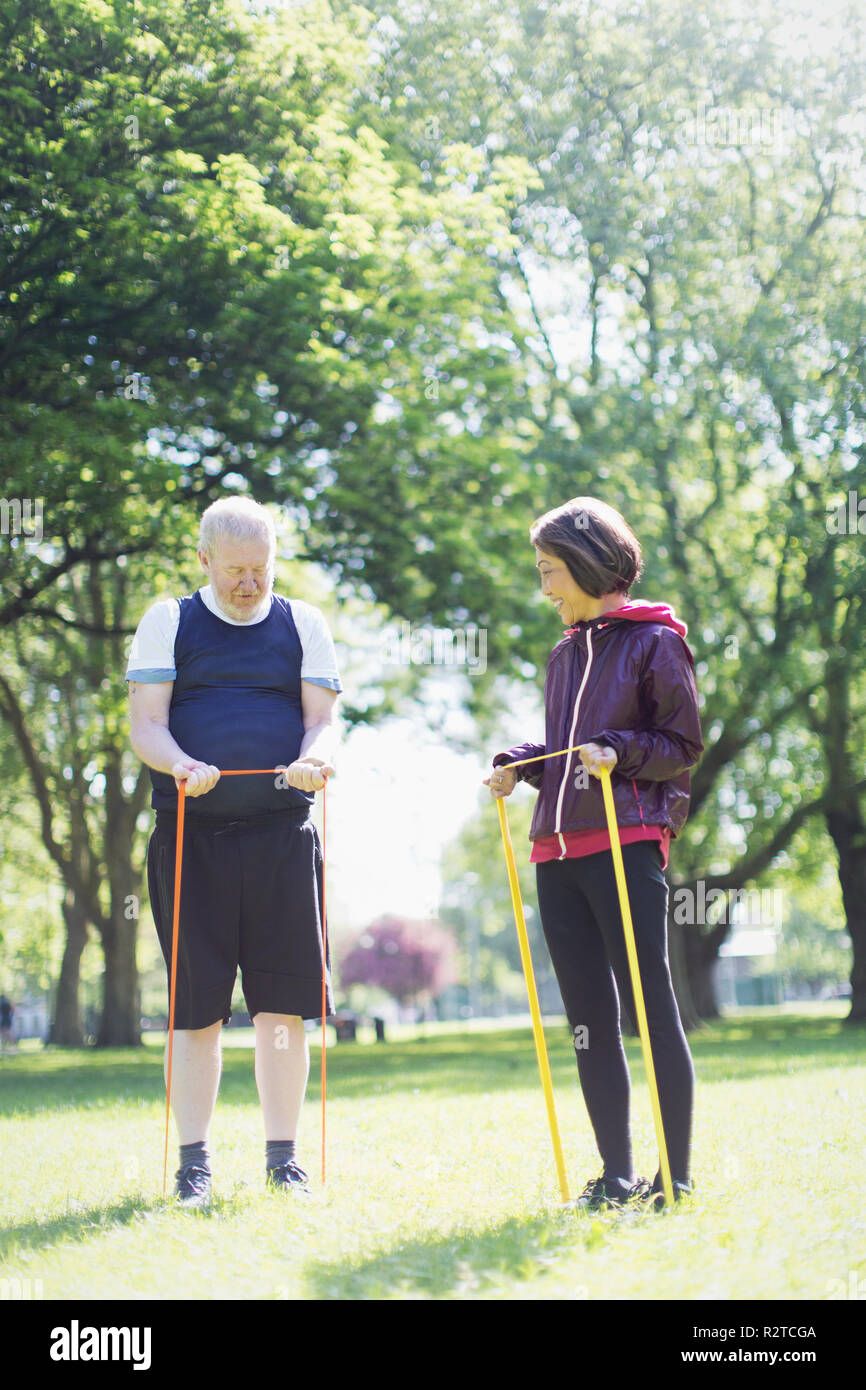 Active Senior paar Ausübung, Stretching mit Widerstand Bänder im sonnigen Park Stockfoto