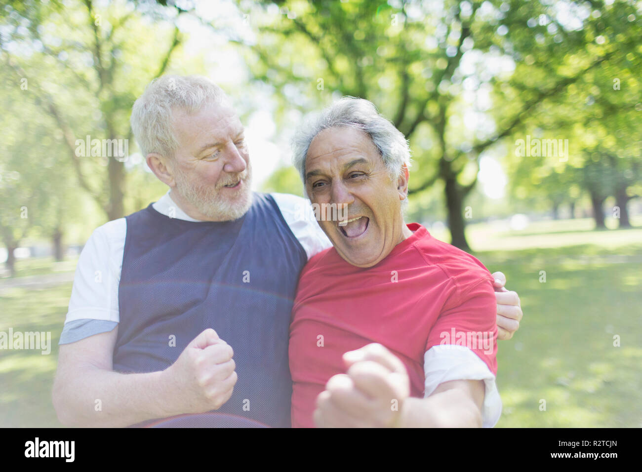 Exuberant aktive ältere Männer Freunde jubeln in Park Stockfoto