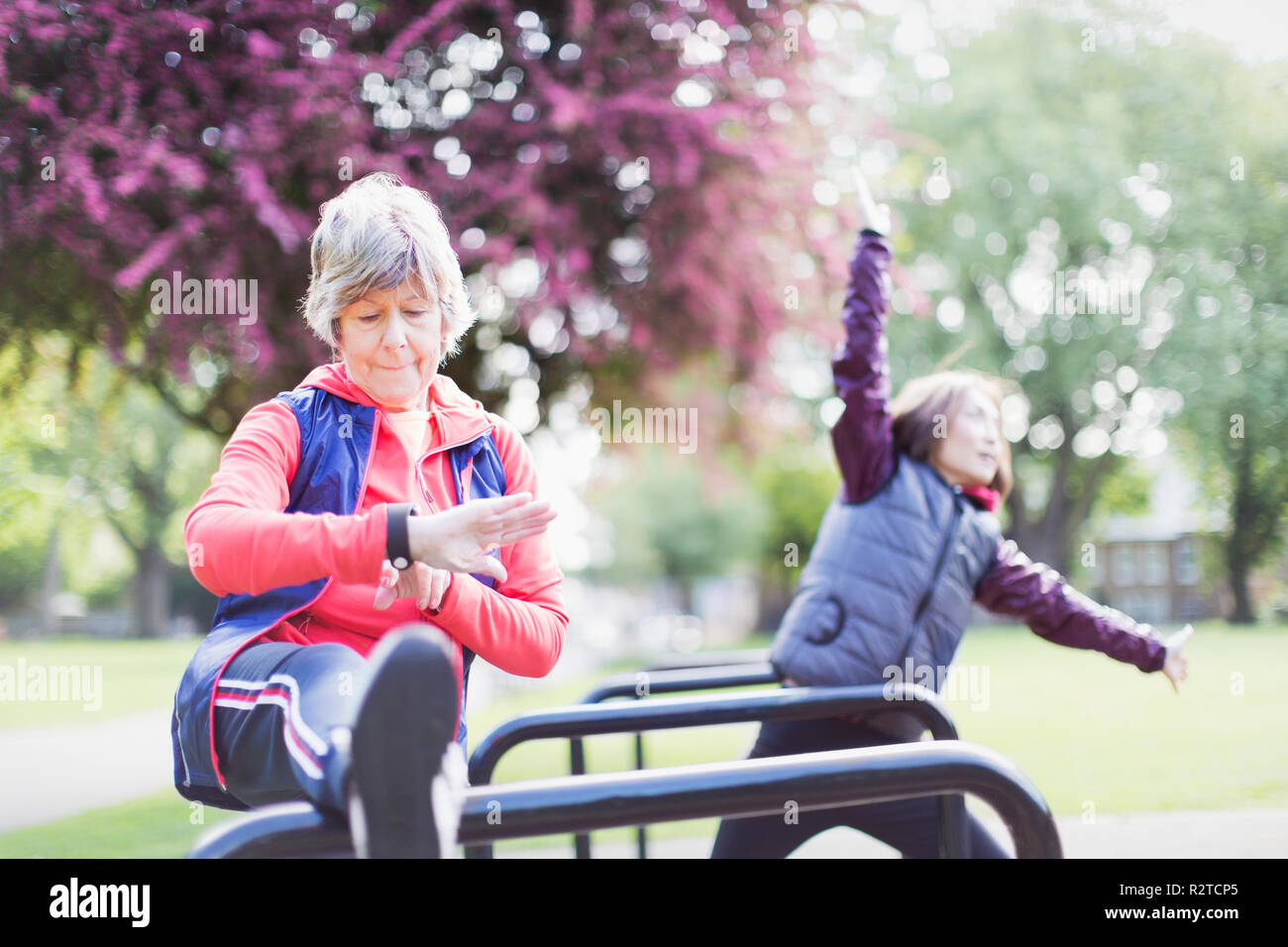 Active Senior Läuferin stretching Bein und Kontrolle smart Watch Stockfoto