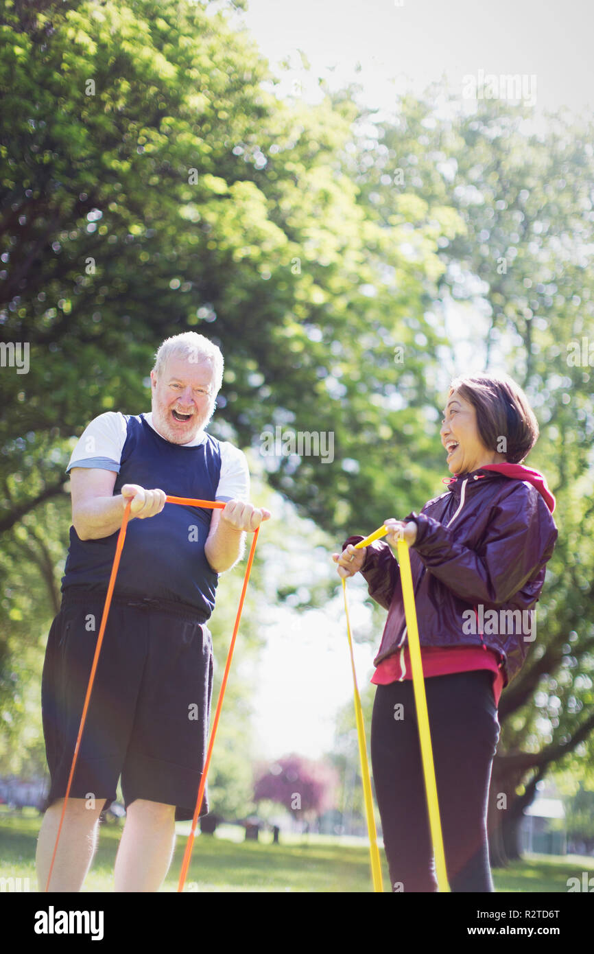 Fit Active Senior Paar trainieren, mit Widerstand Bänder im sonnigen Park Stockfoto