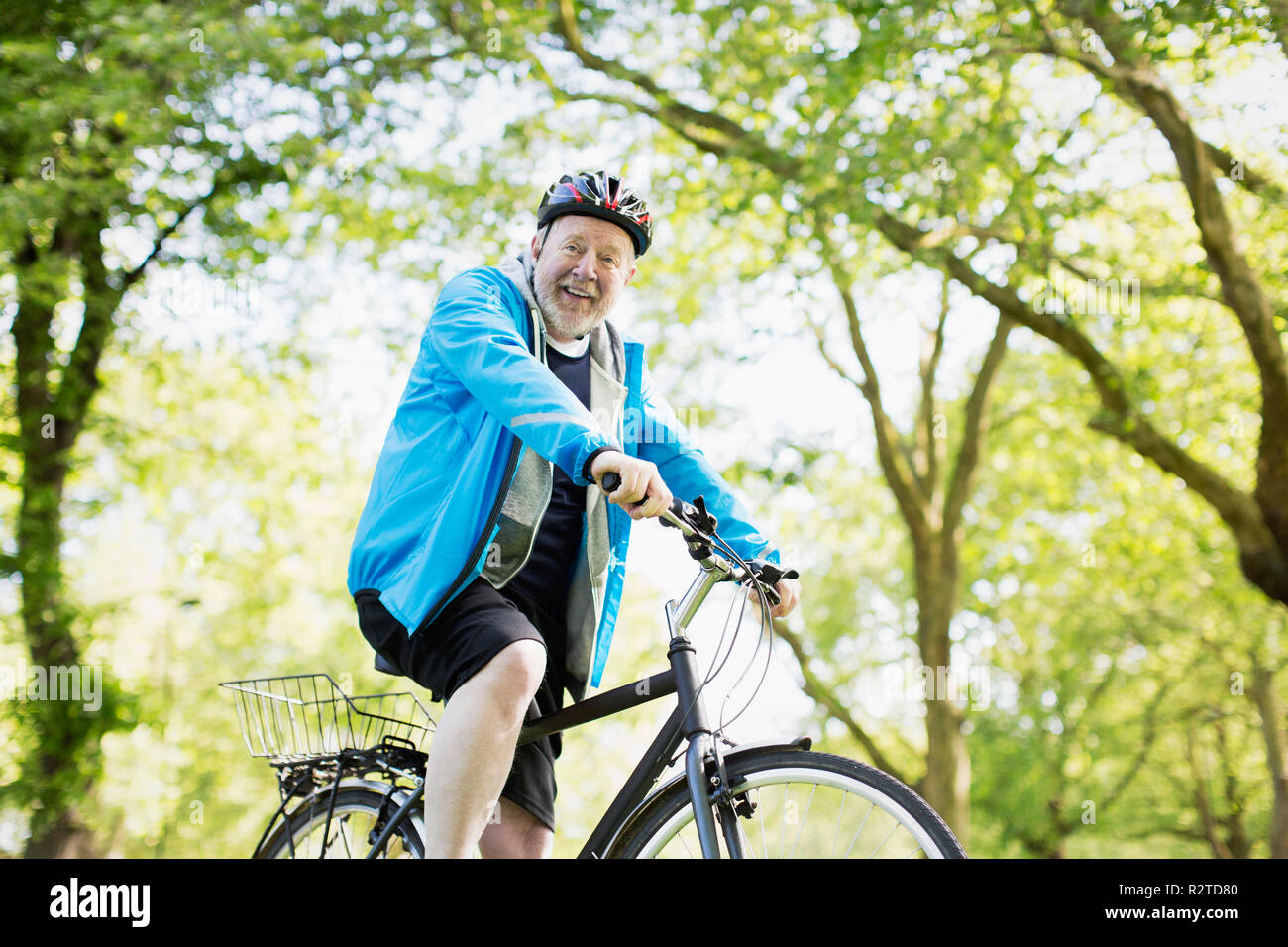 Porträt Lächeln Active Senior Mann reiten Fahrrad im Park Stockfoto
