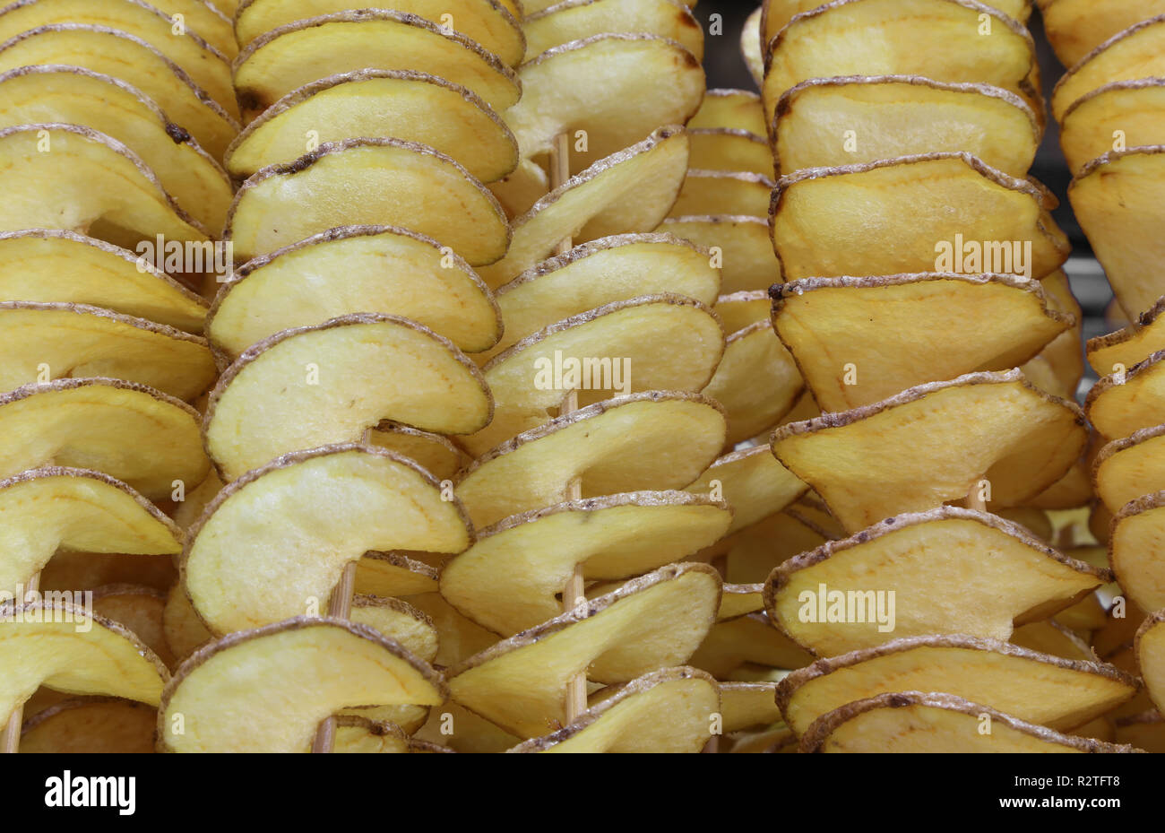 Hintergrund der vielen gelben geschnittene Pommes Frites mit Schale und Spieß, sie zu essen beim Gehen Stockfoto