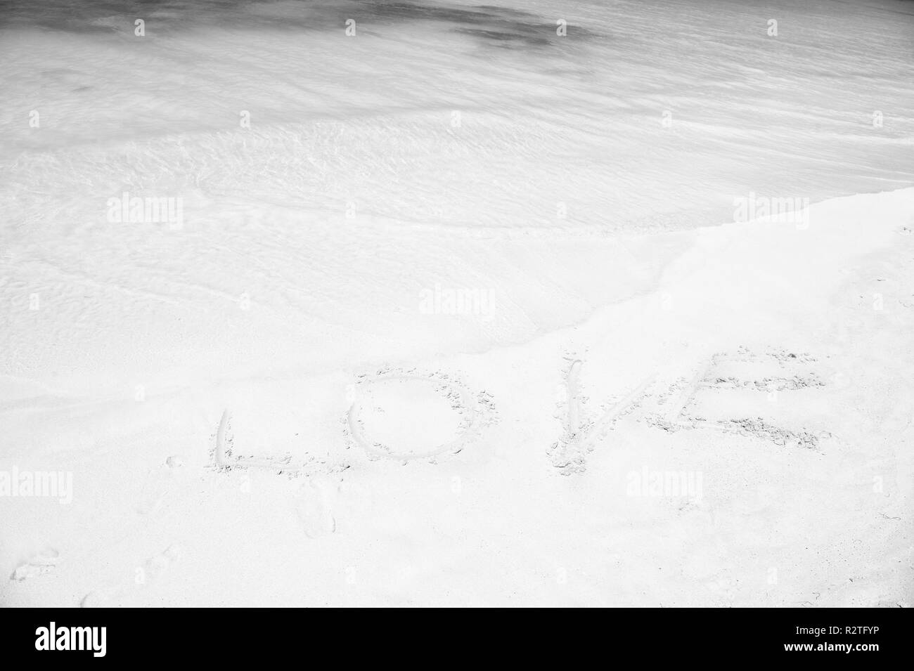 Zeichen Liebe auf den Sandstrand mit Ocean Wave kristallklarem, türkisfarbenem Wasser. Romantischer Ort, perfekte Datum oder vorschlagen. Sand Beach Resort in Antigua von den Touristen sehr beliebt. Romantische Ferienhäuser Ozean Küste. Stockfoto