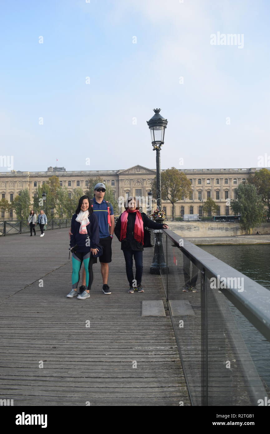 Völker auf der Fußgängerbrücke Pont des Arts auf dem Fluss Seine und Menschen zu Fuß über eine Fußgängerbrücke über die Seine, der Louvre, Stockfoto