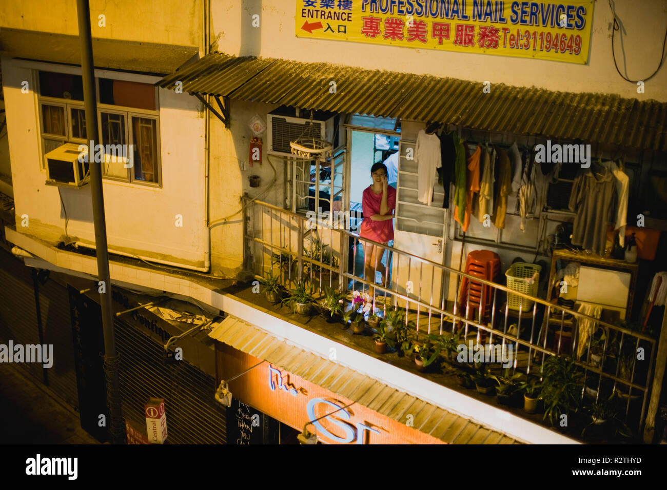 Portrait einer jungen Frau, die in der Tür, während Sie telefonieren auf dem Balkon einen kleinen inneren City Apartment in der Nacht. Stockfoto