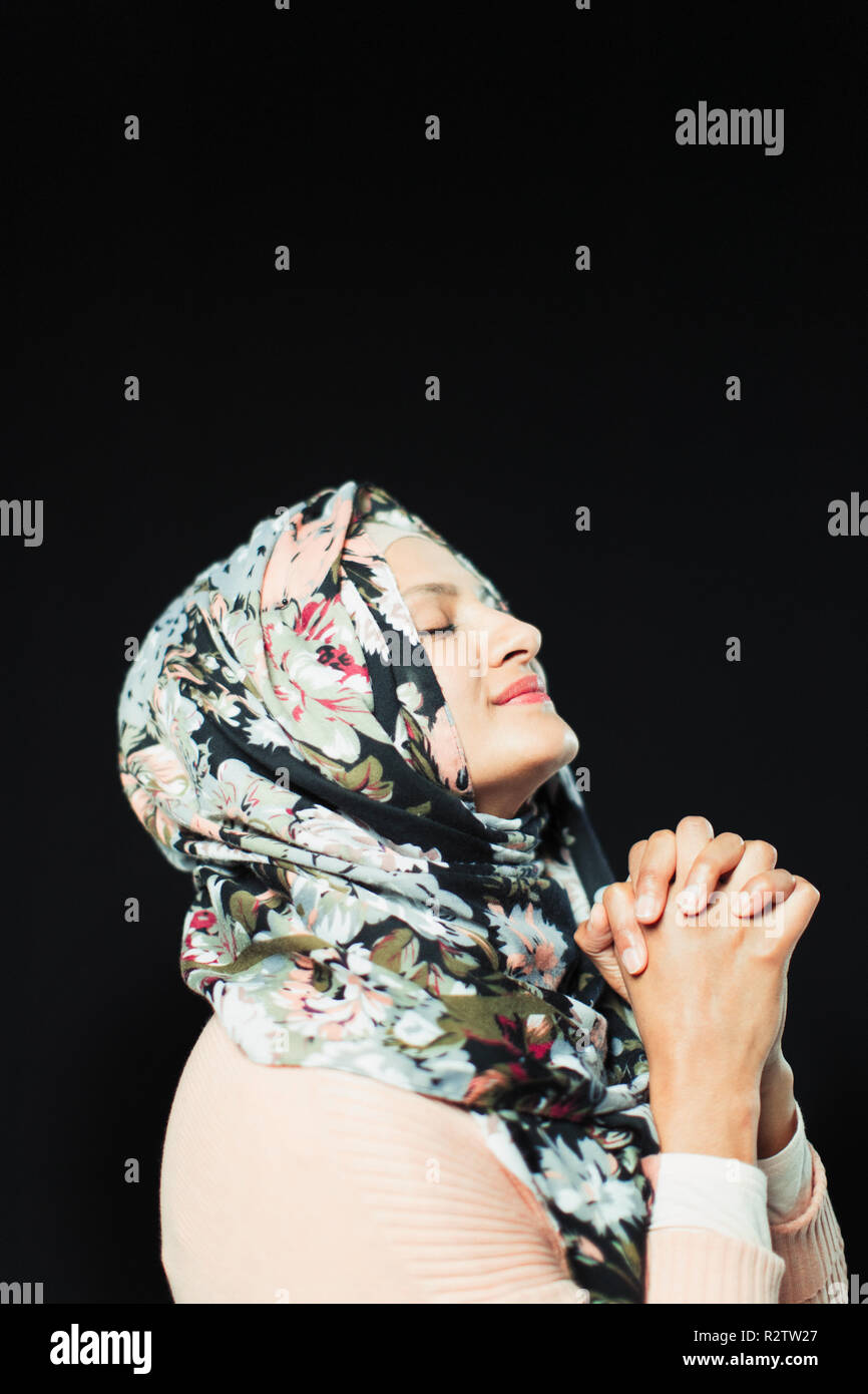 Heitere Frau in floralen Hijab beten Stockfoto