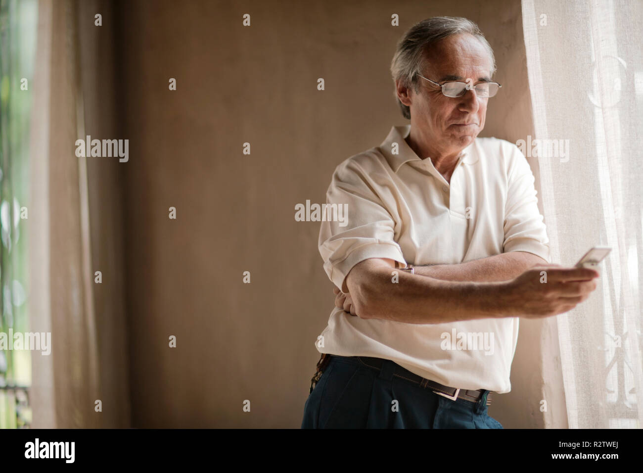 Älterer Mann mit Brille sieht, auf sein Handy. Stockfoto