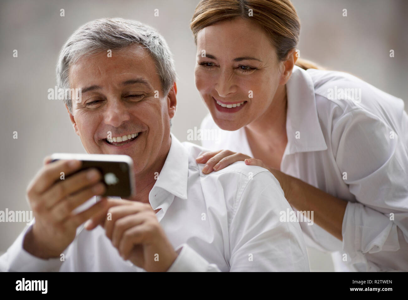 Paar mittleren Alters Lächeln, während bei einem tragbaren Gerät Informationen suchen. Stockfoto