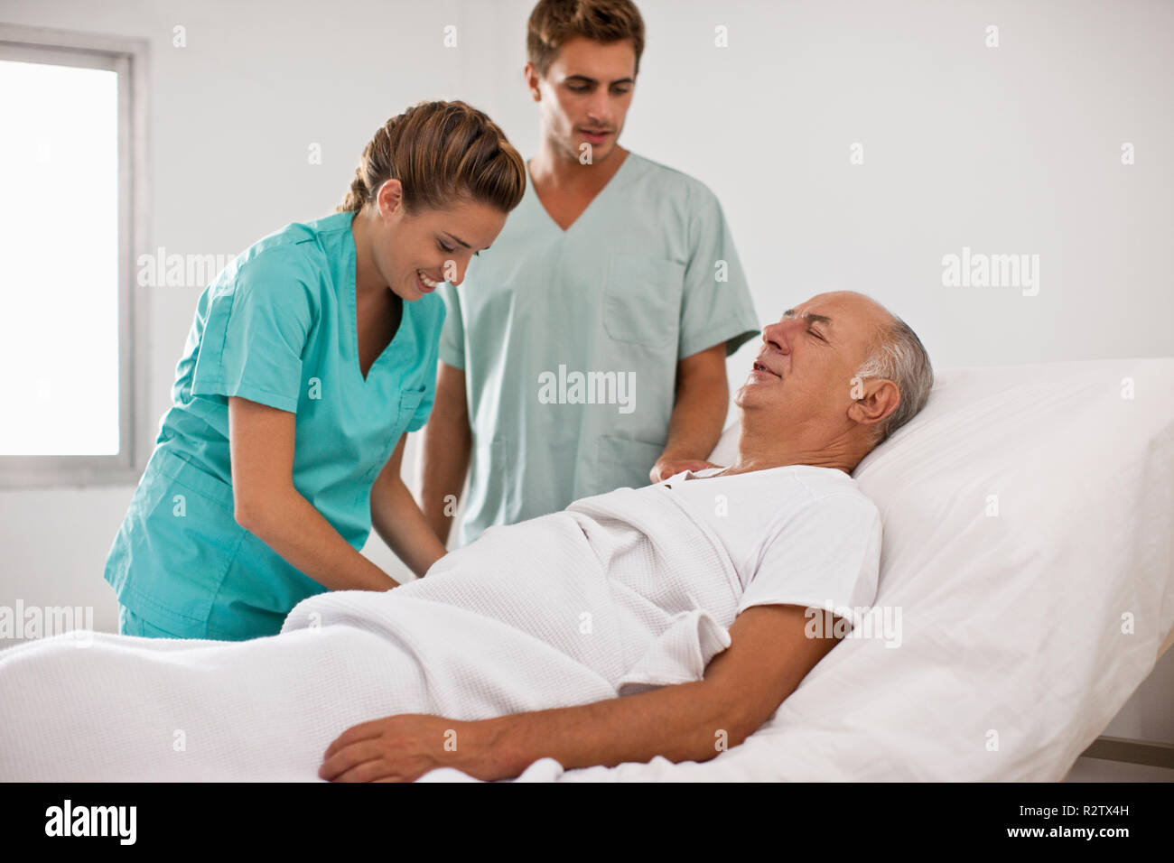 Ältere männliche Patienten schloss seine Augen, während Sie einen medizinischen Test von zwei Krankenschwestern. Stockfoto