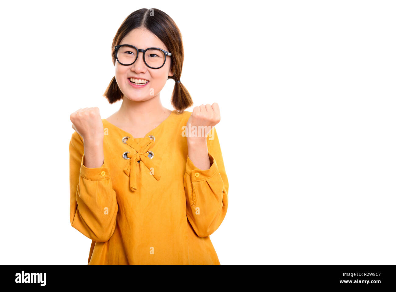 Nachdenkliche junge asiatische Frau glücklich lächelnd, während sie aufgeregt Stockfoto