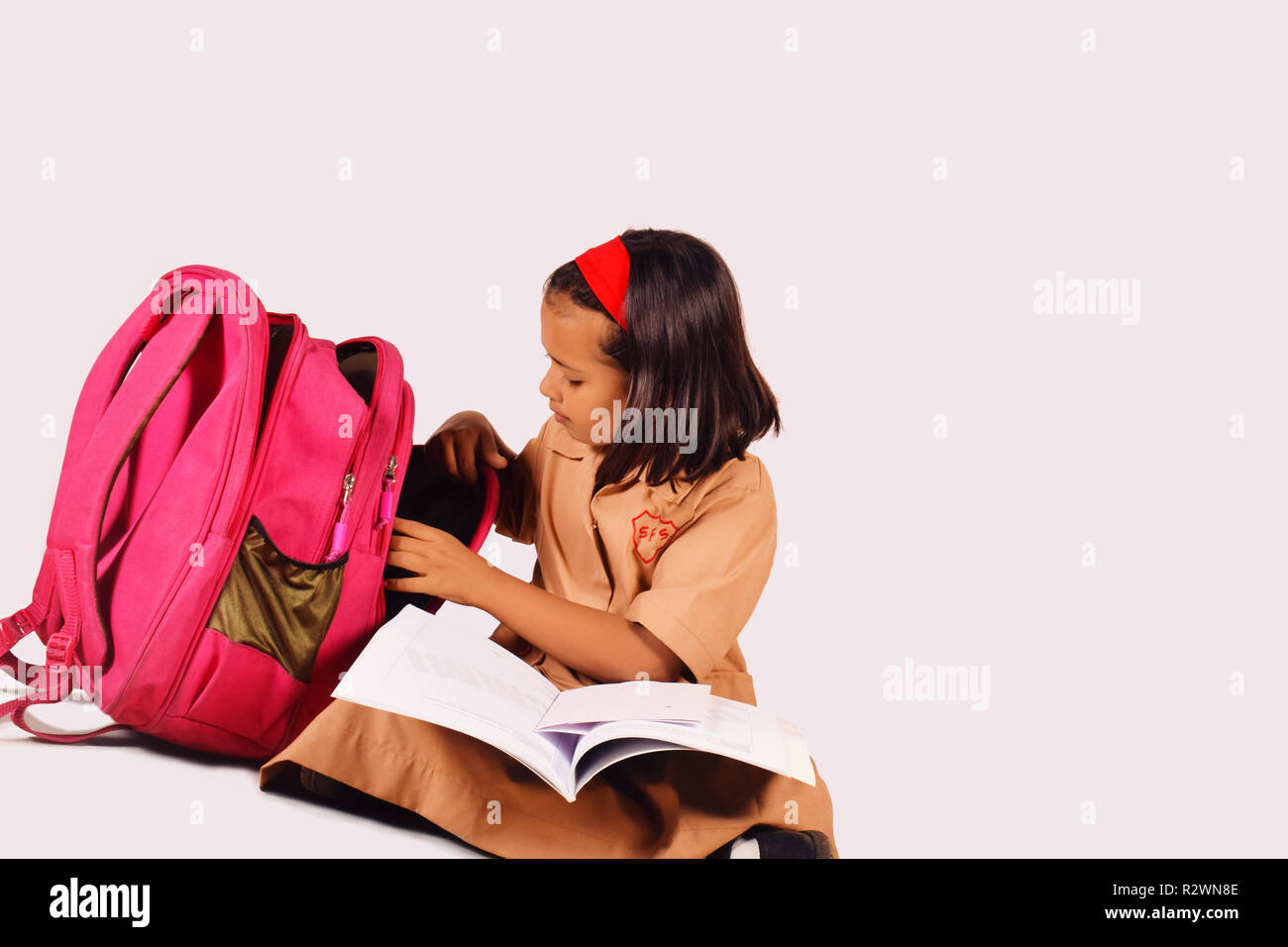 Kleine Mädchen in Schuluniform studieren mit Schultasche auf der Seite. Pune, Maharashtra Stockfoto