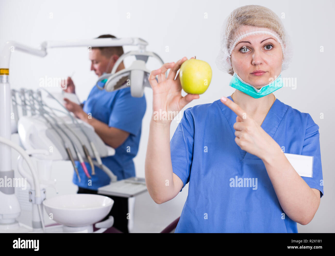 Professionelle Frau Zahnarzt auf gelber Apfel in der Hand beim Stehen in  der Zahnarztpraxis Stockfotografie - Alamy