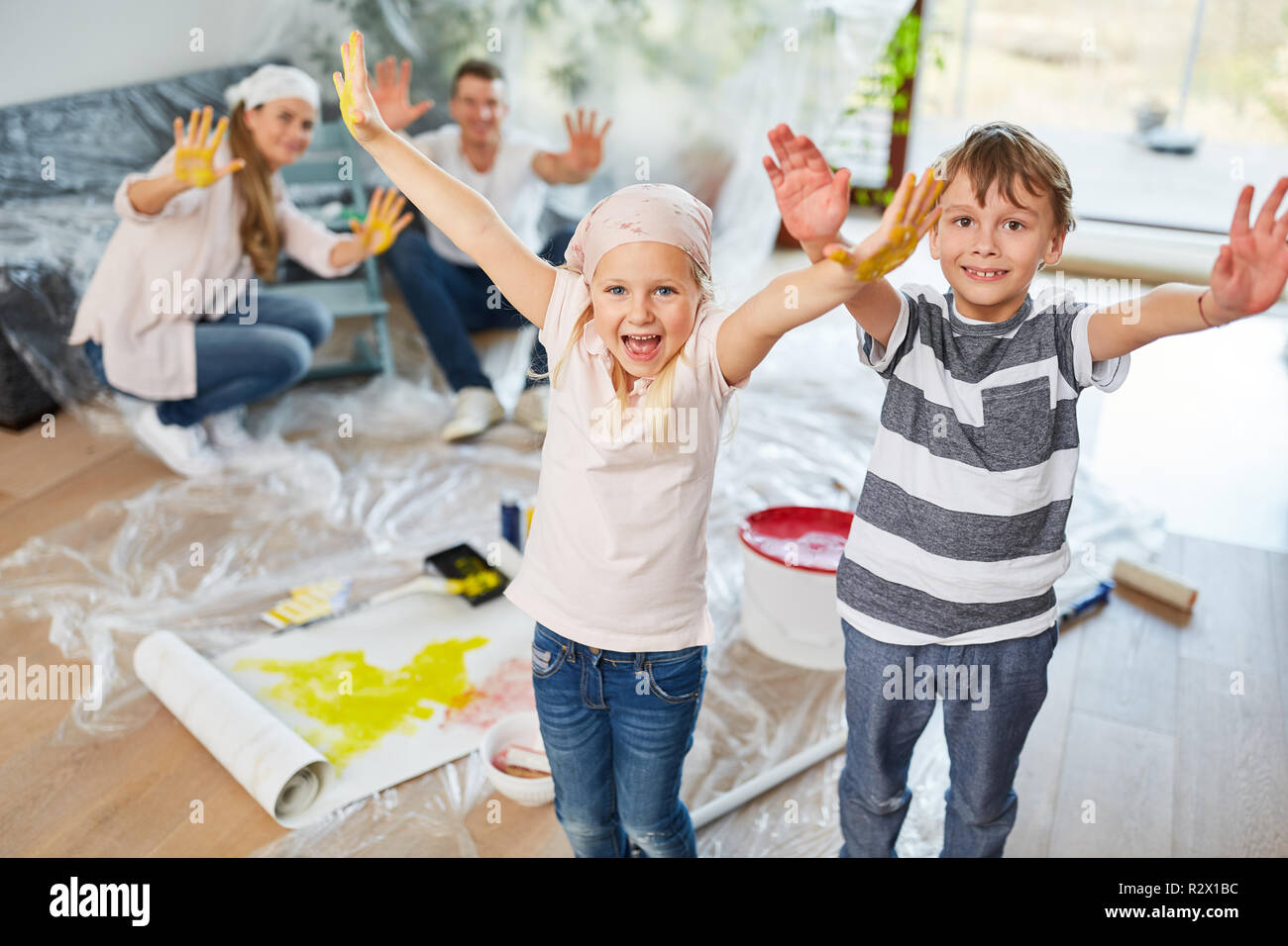 Familie und glückliche Kinder zeigen bunte Hände beim Malen in neues Haus Stockfoto