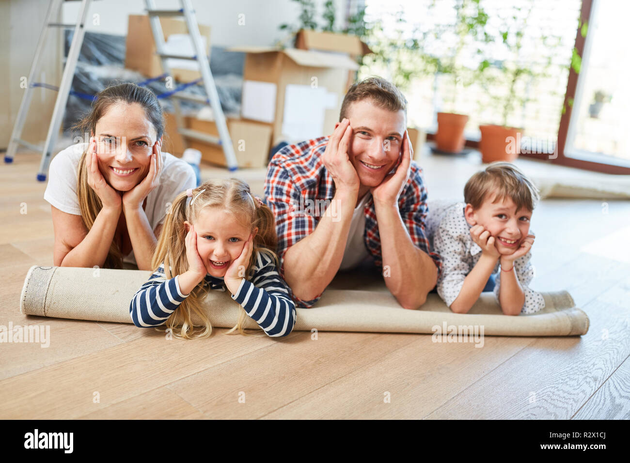 Glückliche Eltern und zwei Kinder ruhen nach dem Umzug in das neue Haus Stockfoto