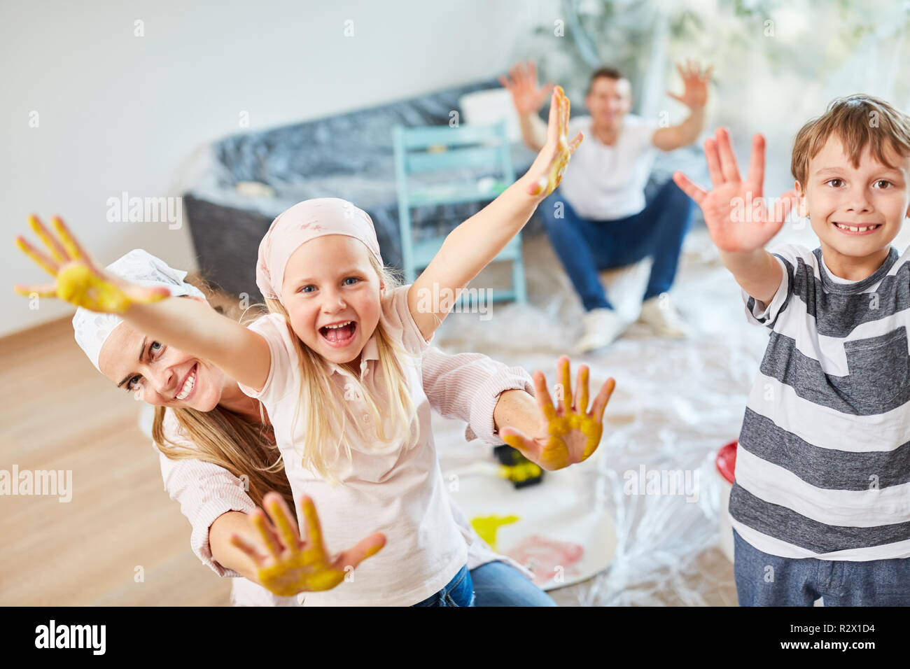 Glückliche Kinder und Eltern zeigen bunte Hände während der Renovierungsarbeiten im neuen Haus Stockfoto