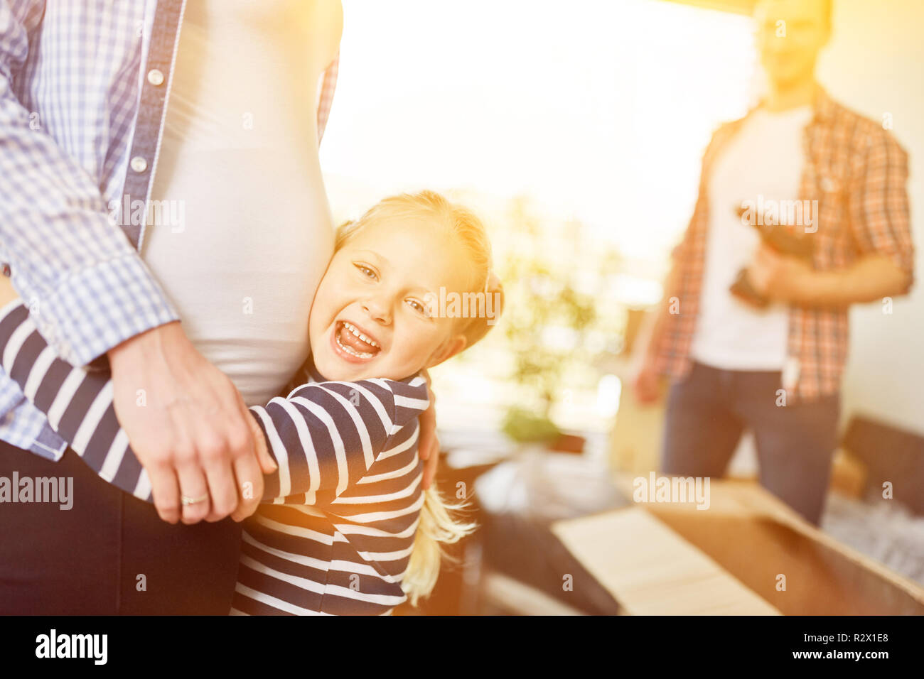 Glückliche Tochter umarmt schwangere Mutter mit Baby Bauch in der neuen Familie zu Hause Stockfoto