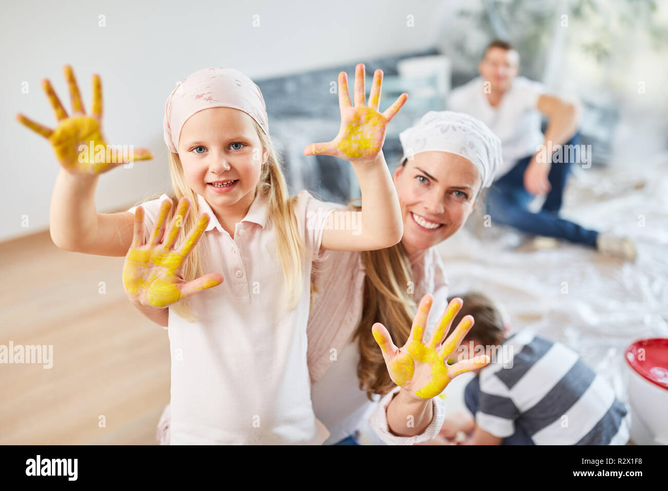 Glückliches Mädchen und Familie mit bunten Händen während der Sanierung Stockfoto