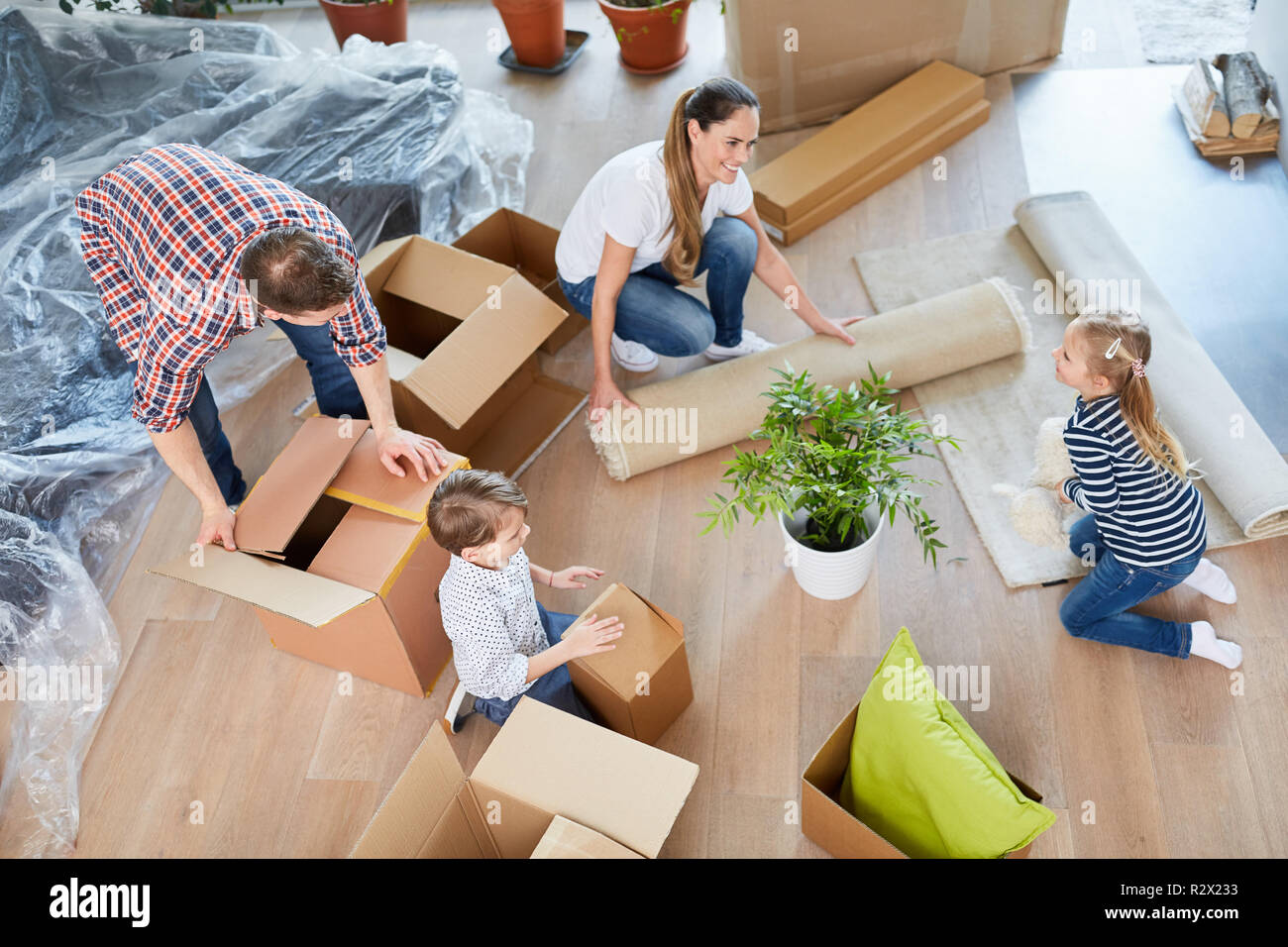 Eltern und zwei Kinder pack Kisten in das neue Haus als Ihre eigene Startseite Stockfoto