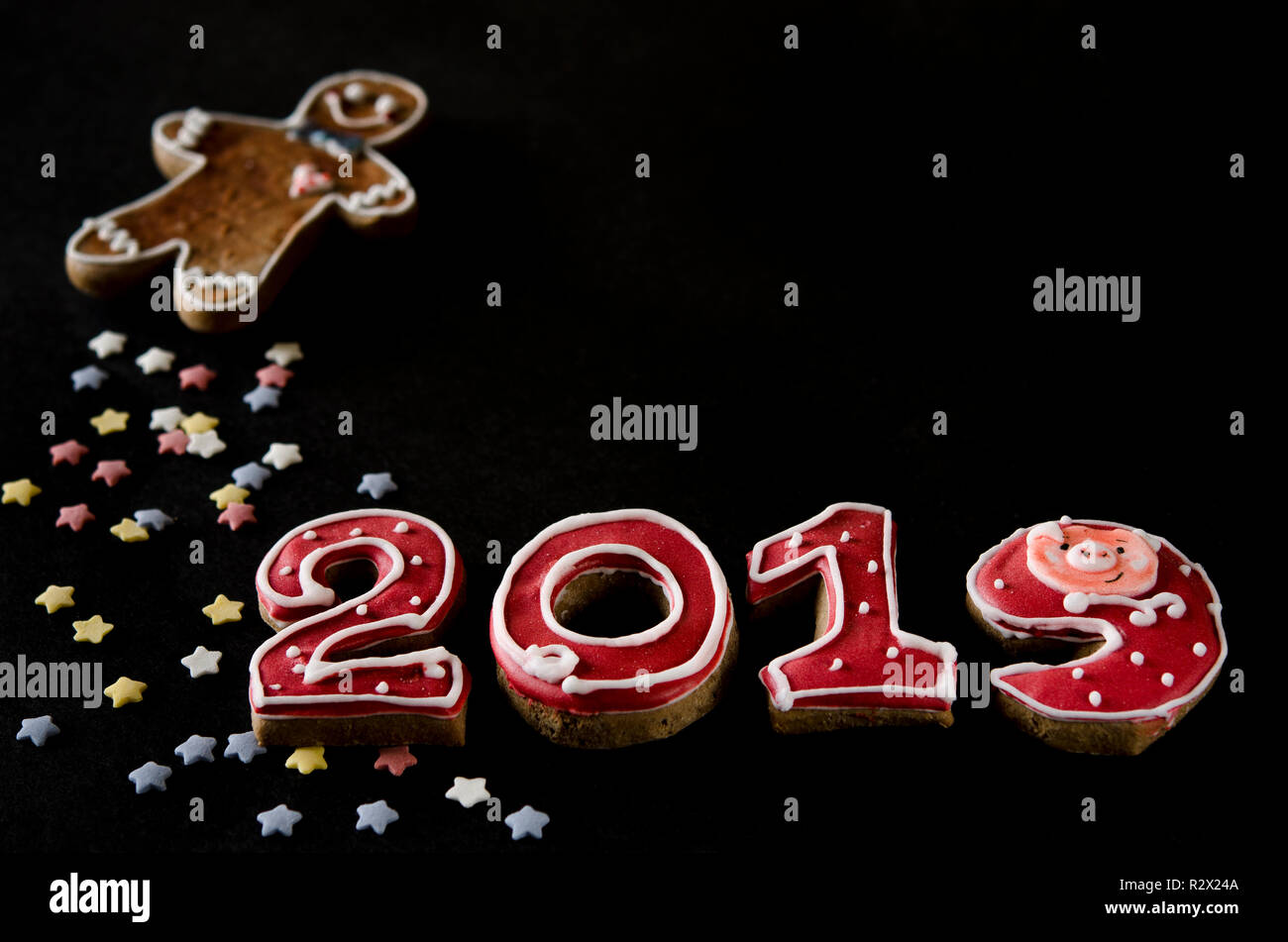 Neues Jahr Karte auf schwarzem Hintergrund Lebkuchen rote Zahlen 2019 mit bunten Sternen und Gingerbread Man Stockfoto