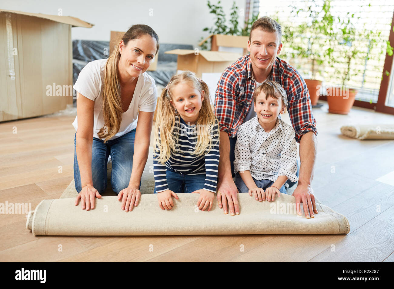 Familie Umzug nach Hause rollen Teppich zusammen mit zwei Kindern Stockfoto