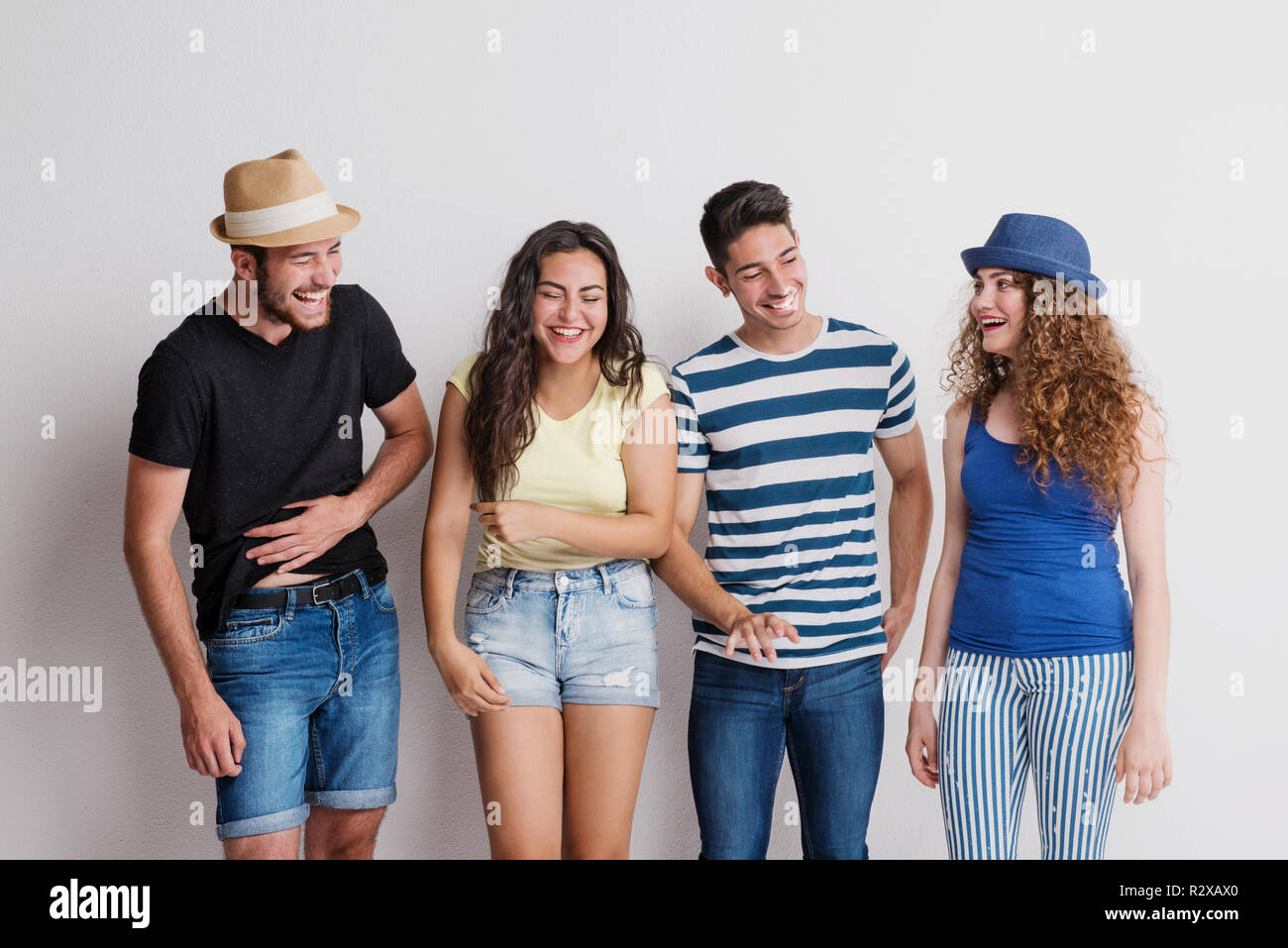Portrait von freudige junge Gruppe von Freunden mit Hut stehend in einem Studio, das Lachen. Stockfoto