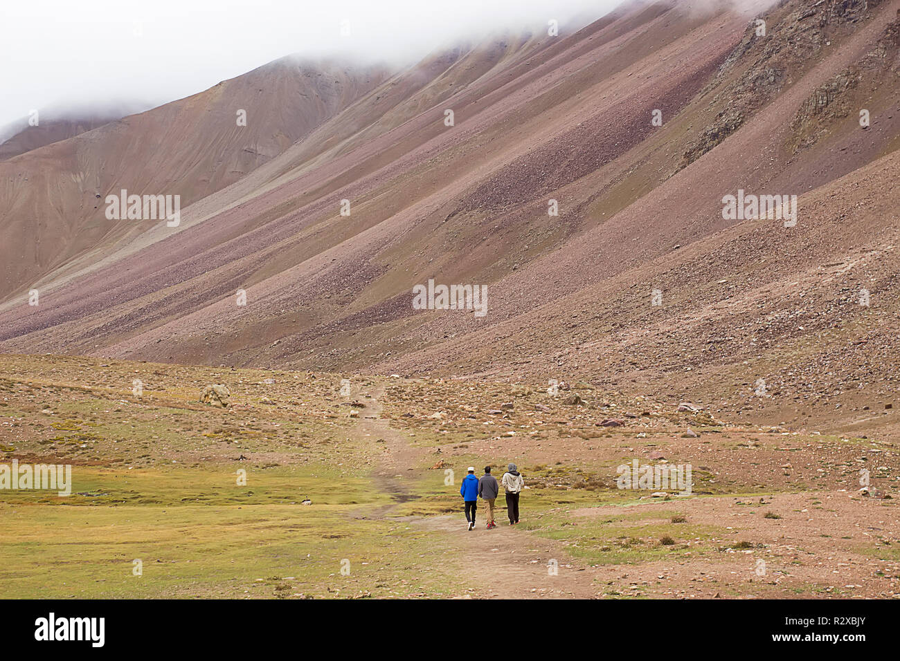 Drei kleine Männer auf dem Hintergrund der großen Berge. Das Konzept der Großen und Kleinen. Stockfoto