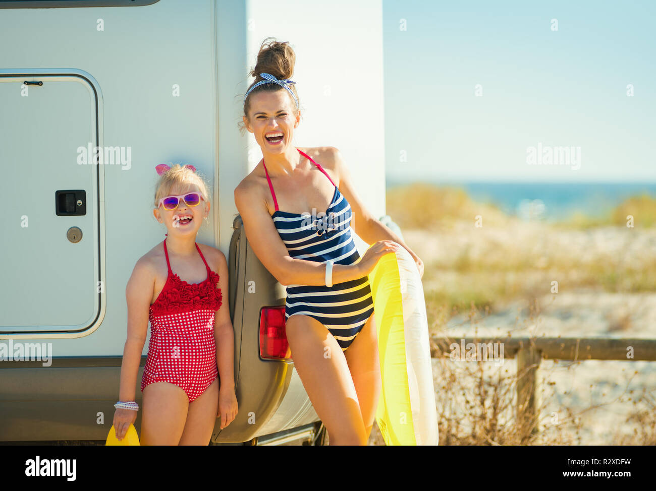 Portrait der glücklichen Mutter und Tochter in Badeanzug mit Gelb  aufblasbarer Rettungsring in der Nähe der Anhänger auf den Strand. Es ist  nichts leichter - Sprung ins t Stockfotografie - Alamy
