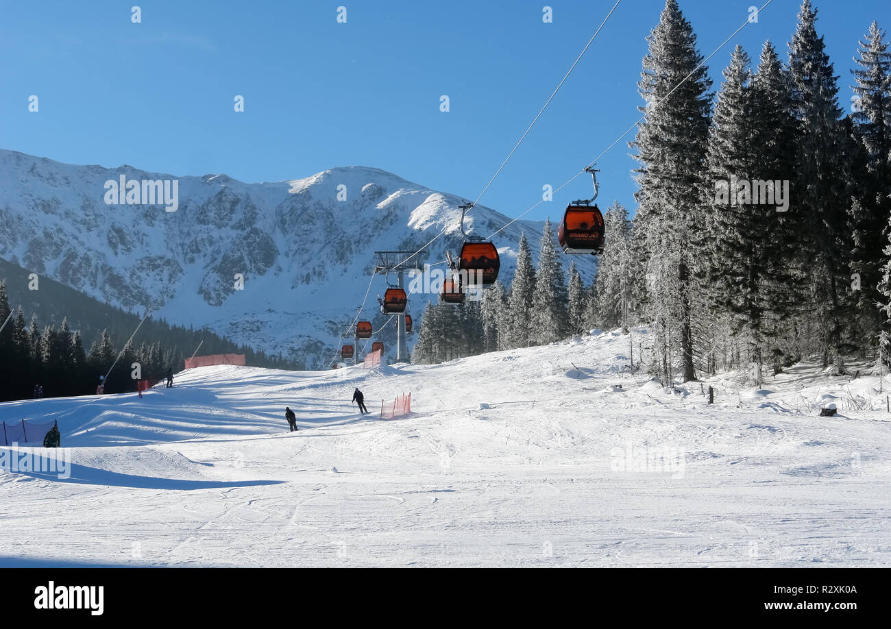 Jasna, Slowakei - Januar 25, 2017: Seilbahn Kabinen und Skifahrer an einem sonnigen Tag auf der Piste im Skigebiet Jasna Niedere Tatra, Slowakei. Stockfoto